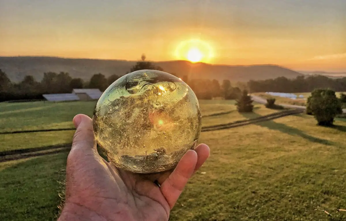 An image of a crystal ball at sunrise at a farm-like backbround